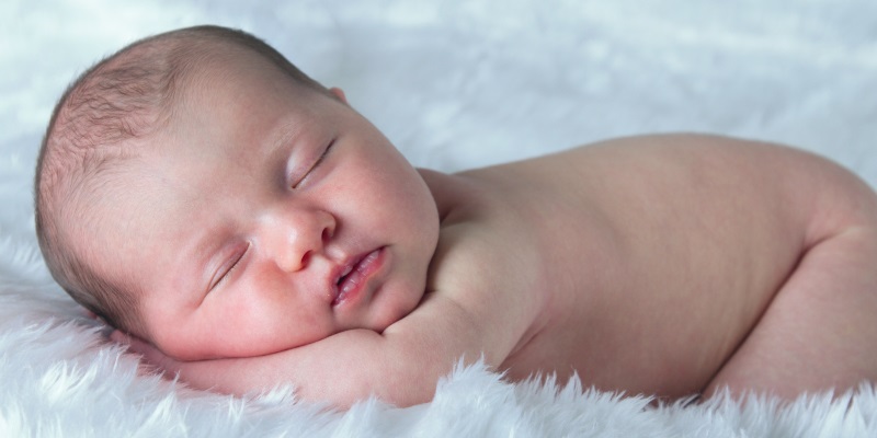 newborn baby sleeping on white blanket
