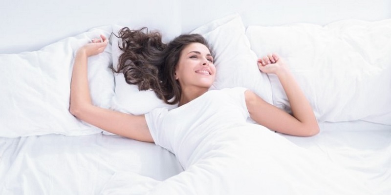 woman lying down in white bed smiling